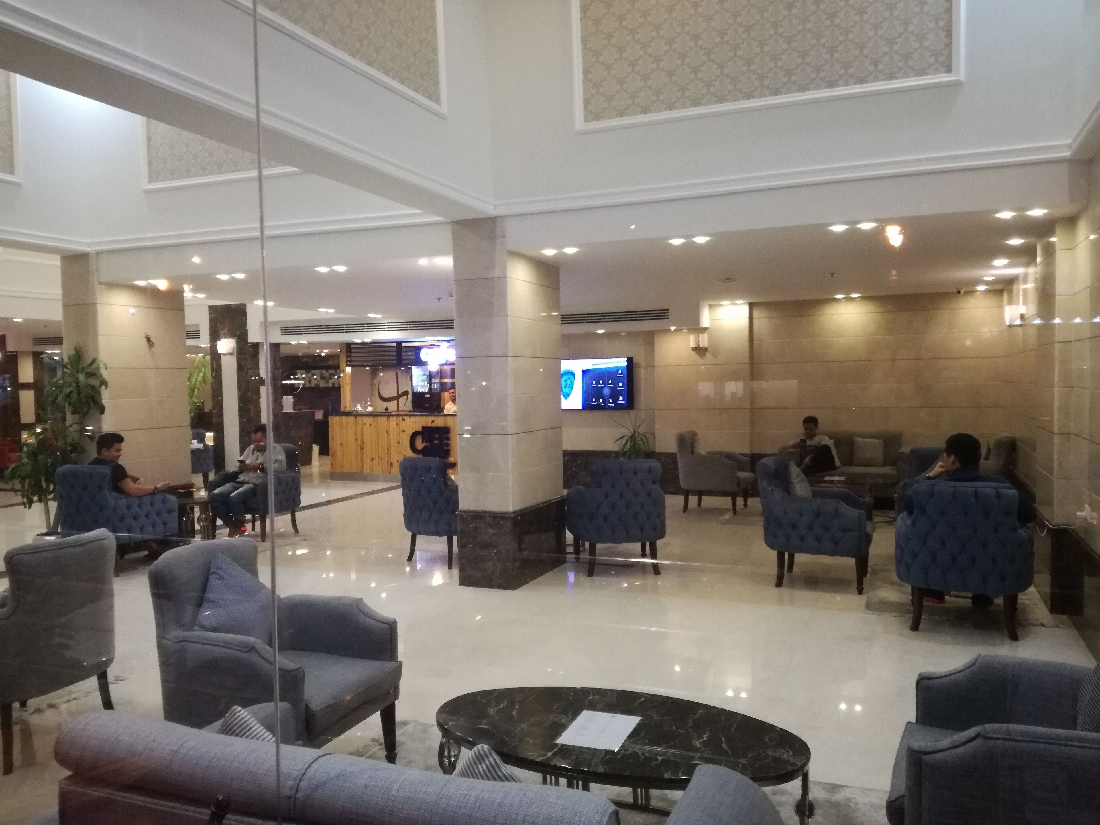 Un amplio vestíbulo con zonas de estar, un mostrador de recepción y una pantalla de televisión.