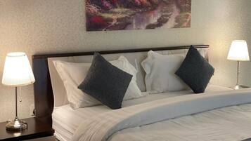 Quarto de hotel com uma cama bem arrumada, duas luminárias de cabeceira e um quadro grande sobre a cama.