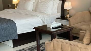 Quarto de hotel com cama, mesas de cabeceira, uma cadeira e um tapete.