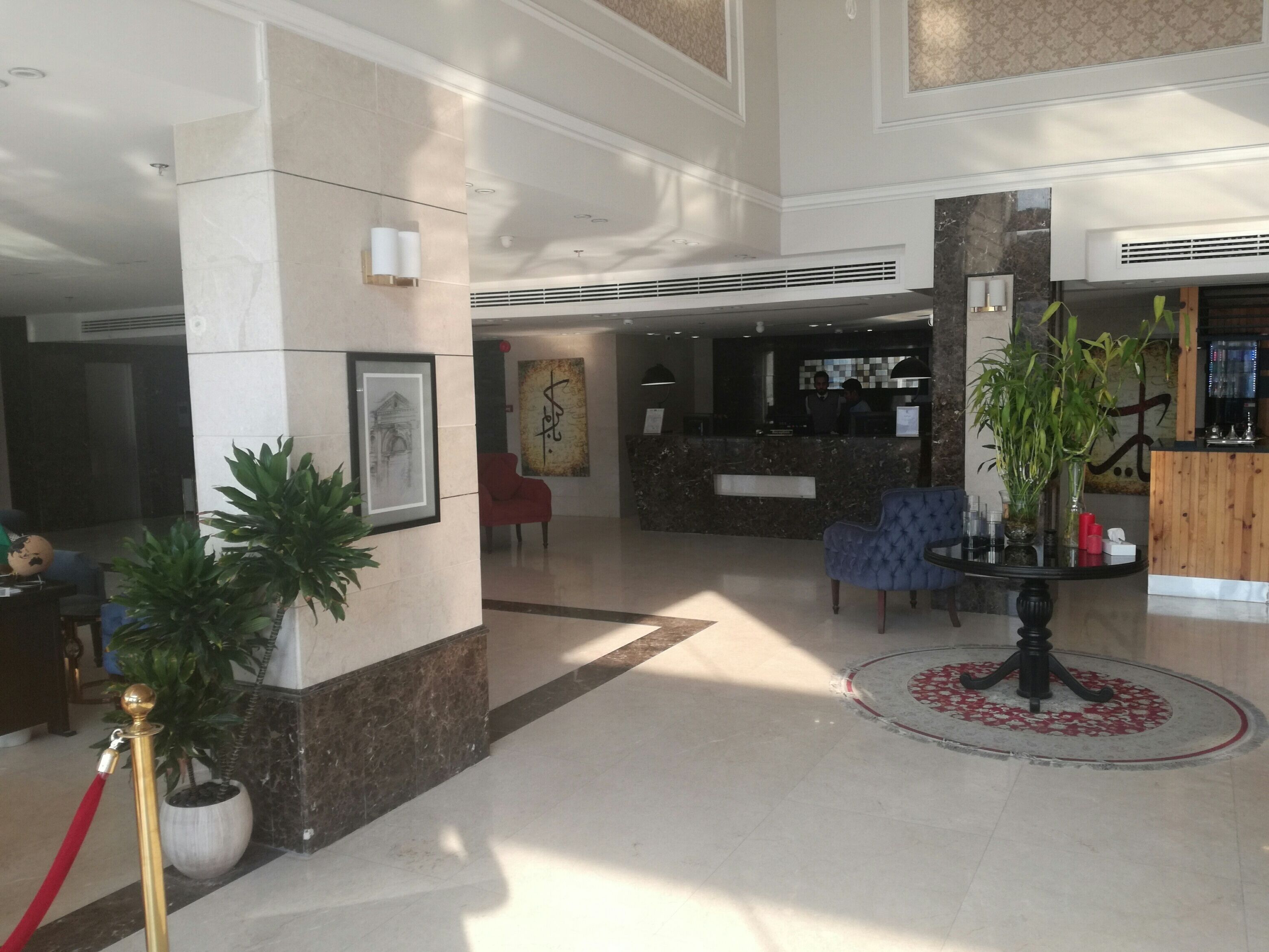 A spacious lobby with a reception desk, seating area, and decorative plants.