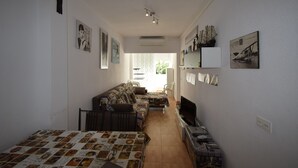 A narrow room with a sofa, a TV, and a table with a magazine.