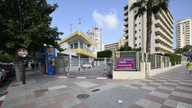 A hotel entrance with a gated entrance, a sign for 'Hotel Servic Group Venus', and a 'Cafe-bar' sign.