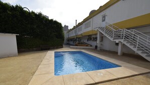A swimming pool with a white and yellow building in the background.