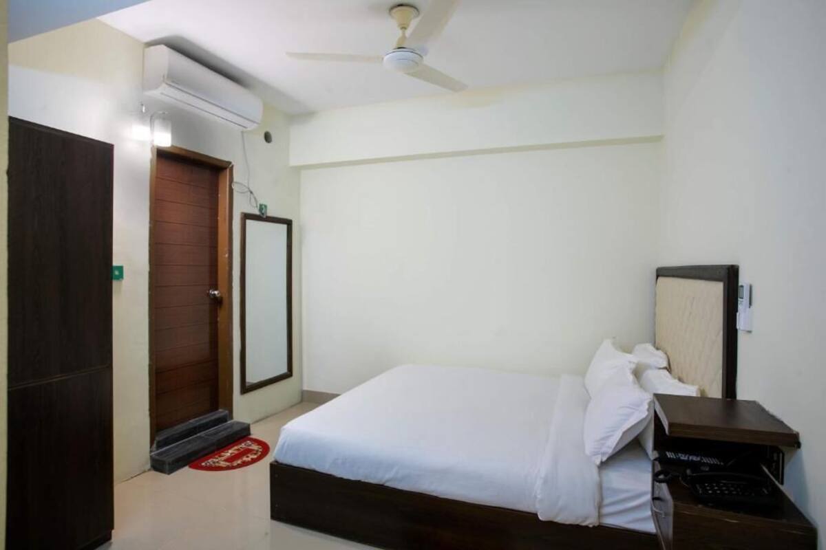 Ein Schlafzimmer mit einem Bett, einem Schreibtisch, einem Stuhl, einem Kleiderschrank und einem Deckenventilator.