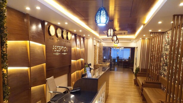 A reception area with a wooden reception desk, a clock, and a reception sign. - Hotel Grand View (Sylhet)