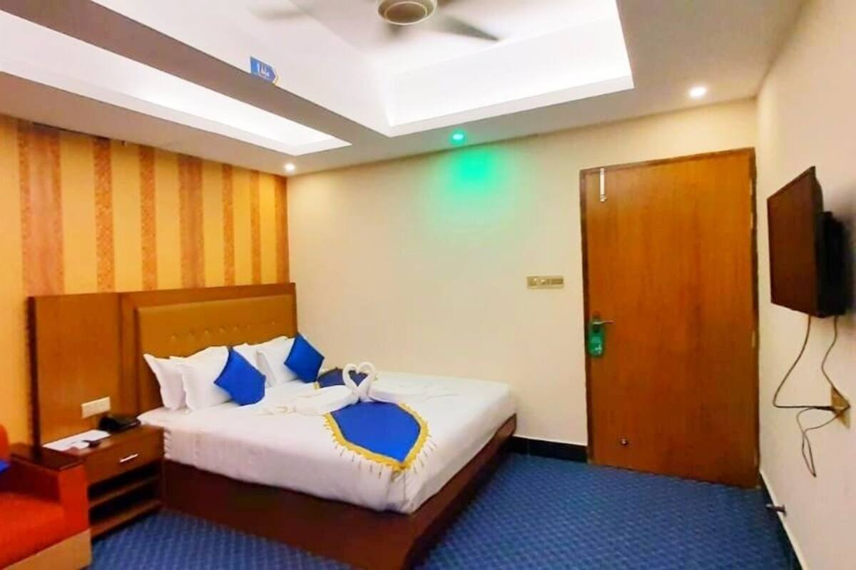 Ein Hotelzimmer mit Bett, Schreibtisch, Stuhl, Fernseher und Kleiderschrank.