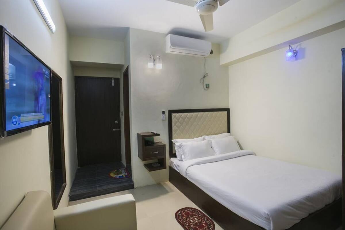 Ein Hotelzimmer mit Bett, Fernseher, Deckenventilator und Klimaanlage.