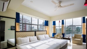 A hotel room with a large bed, two armchairs, a small table, and a ceiling fan. - Hotel Grand View (Sylhet)