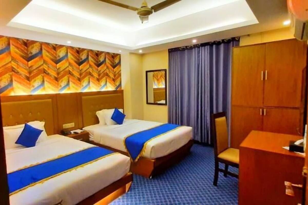Ein Hotelzimmer mit zwei Betten, einem Schreibtisch, einem Kleiderschrank und einem Deckenventilator.