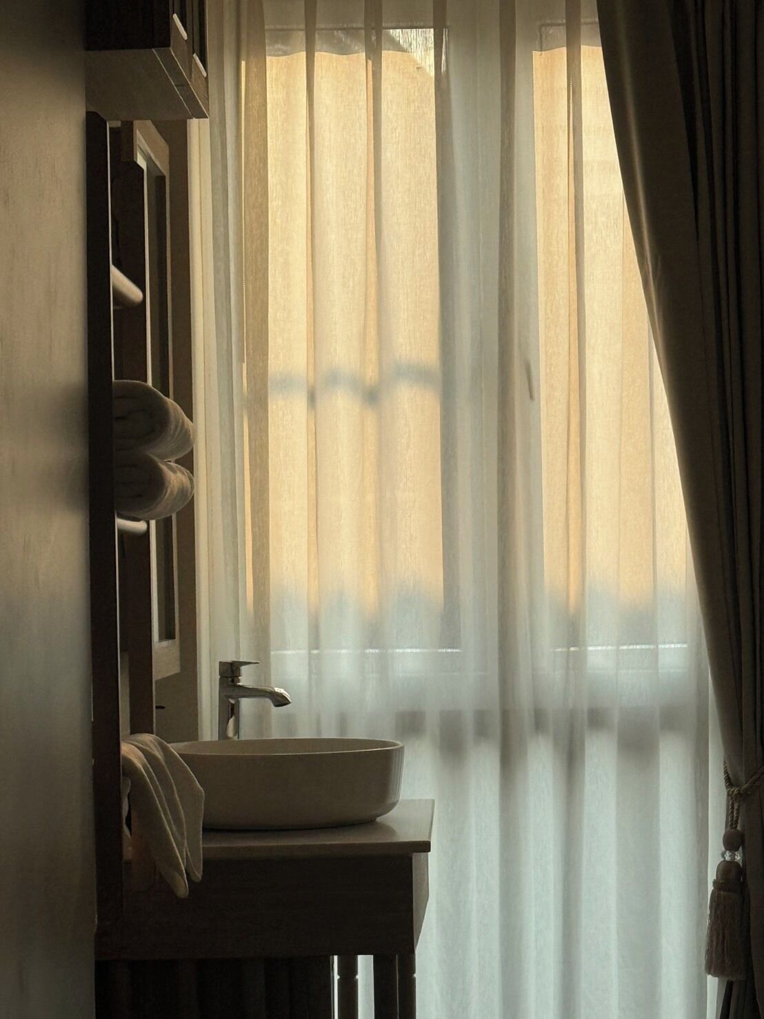 A bathroom with a sink, mirror, and curtains.