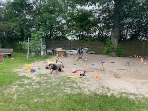 Ein Sandspielplatz mit Spielzeug und einer Holzkonstruktion in Form eines Bootes.