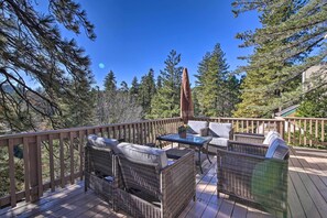 Eine Terrasse mit Korbmöbeln und einem Tisch, umgeben von Bäumen.