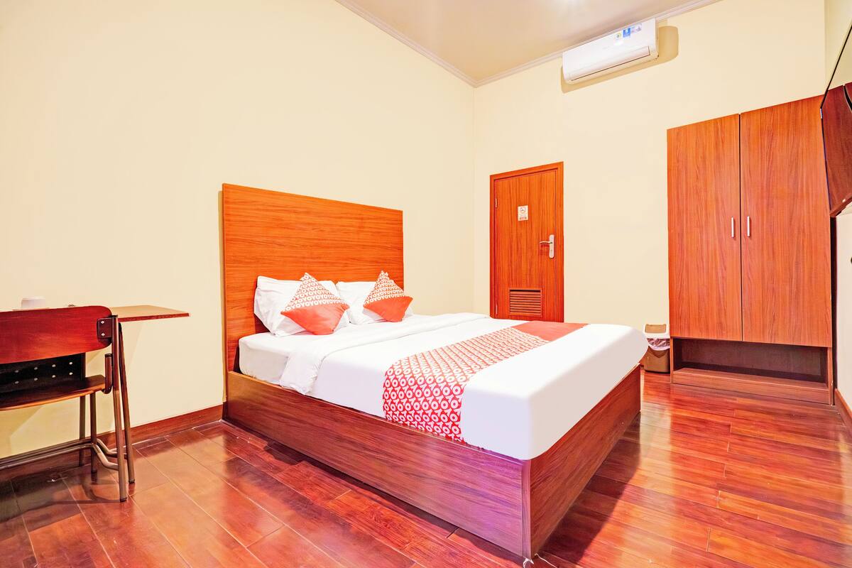 A hotel room with a wooden bed, a desk, and a wardrobe.