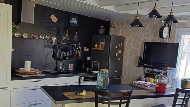 Une cuisine moderne dotée d’un îlot central, de tabourets de bar, de luminaires suspendus et d’une grande fenêtre.