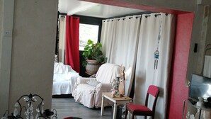 Un salon confortable avec un fauteuil à rayures, une petite table et un téléviseur.