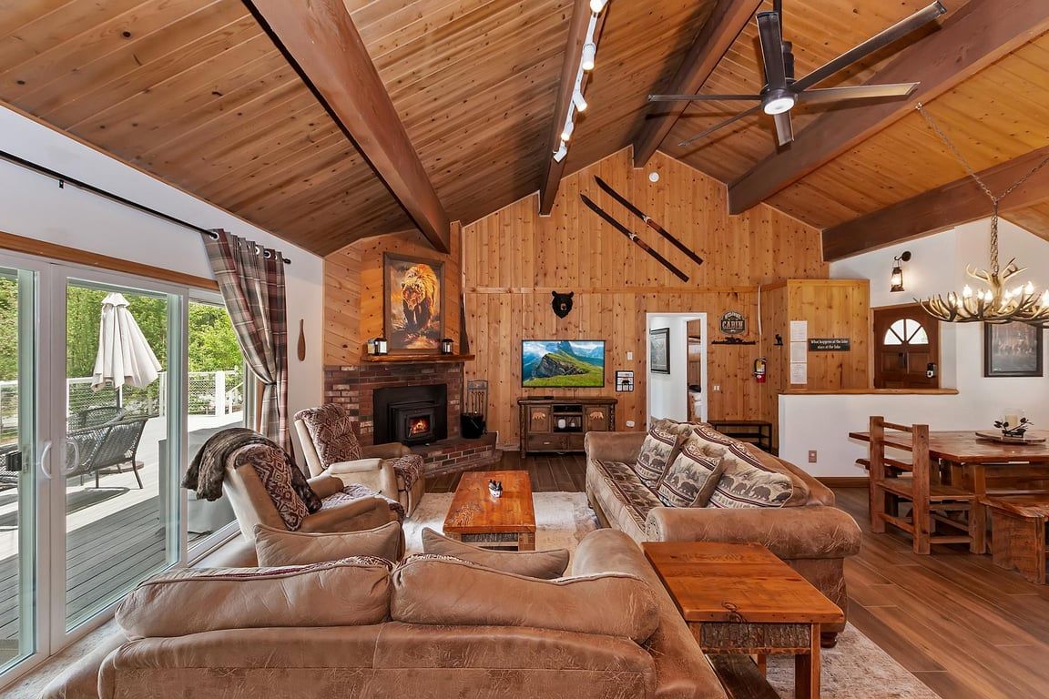 A spacious living room with a fireplace, leather sofas, a wooden dining table, and a television.