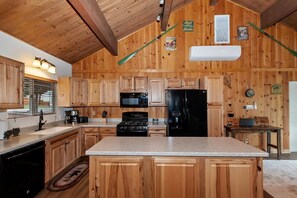A kitchen with wooden cabinets, a granite countertop, a black refrigerator, and a microwave. - Eagle Point Cabin Backing to 7 Acres of Preserve! HOT TUB!  A/C! PET FRIENDLY! Walk to Lake & Shuttles! (Big Bear Lake)