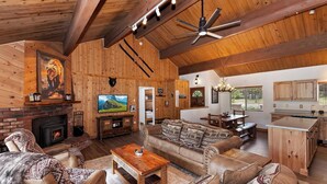 A spacious living area with a fireplace, a television, and a large sofa. - Eagle Point Cabin Backing to 7 Acres of Preserve! HOT TUB!  A/C! PET FRIENDLY! Walk to Lake & Shuttles! (Big Bear Lake)
