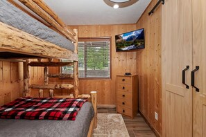A cabin-style bedroom with a bunk bed, a television, a window with blinds, and a wooden wardrobe. - Eagle Point Cabin Backing to 7 Acres of Preserve! HOT TUB!  A/C! PET FRIENDLY! Walk to Lake & Shuttles! (Big Bear Lake)