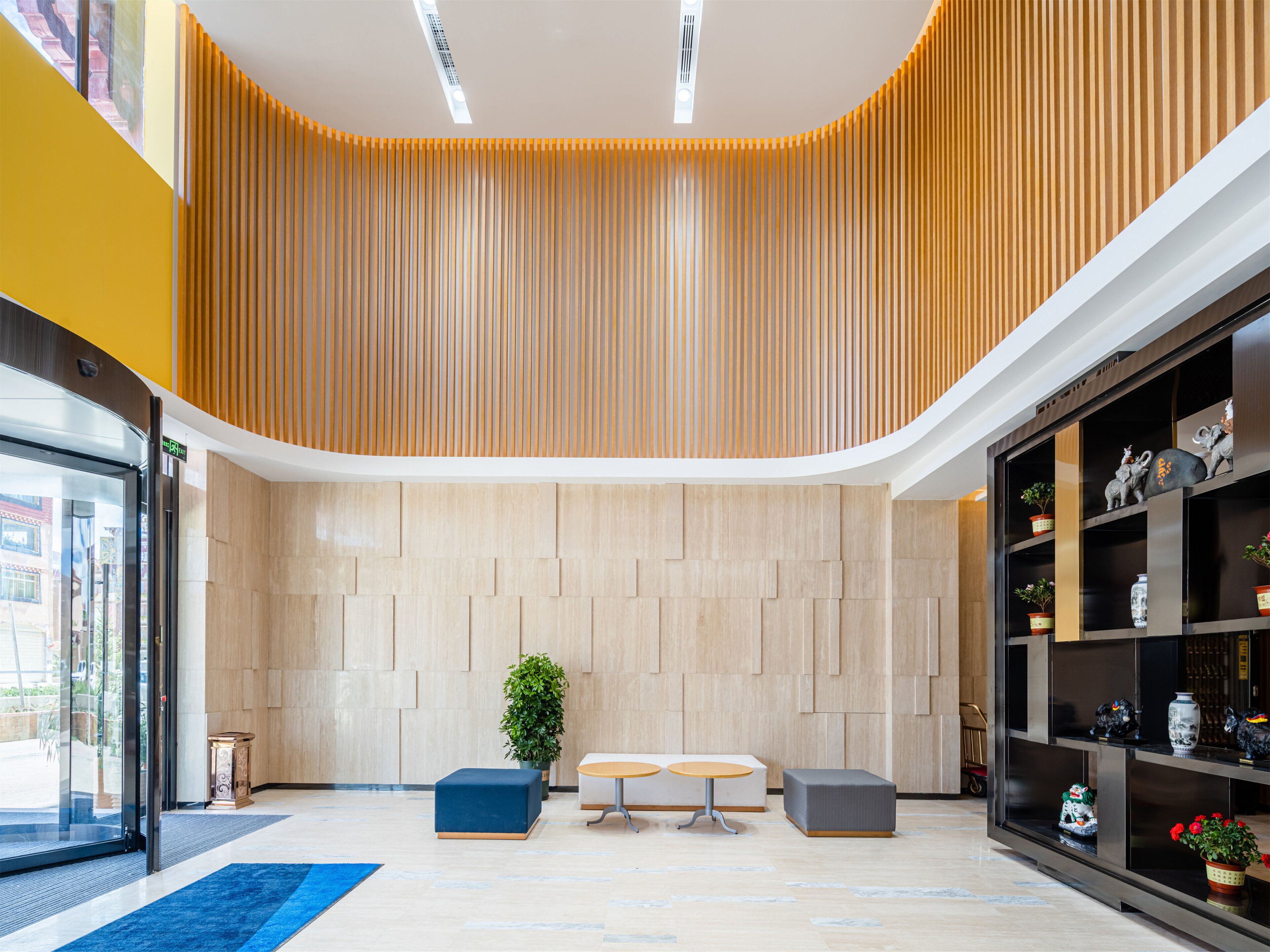 A modern lobby with a curved ceiling, a reception desk, seating area, and a display of decorative items.