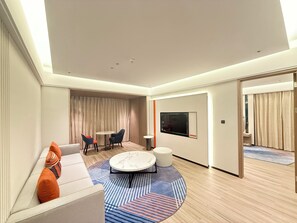A modern hotel room with a sofa, two chairs, a coffee table, a TV, and a large window. - Holiday Inn Express Litang by IHG (Garze)
