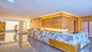 A modern reception desk with a marble top, a large map on the wall, and a glass partition.