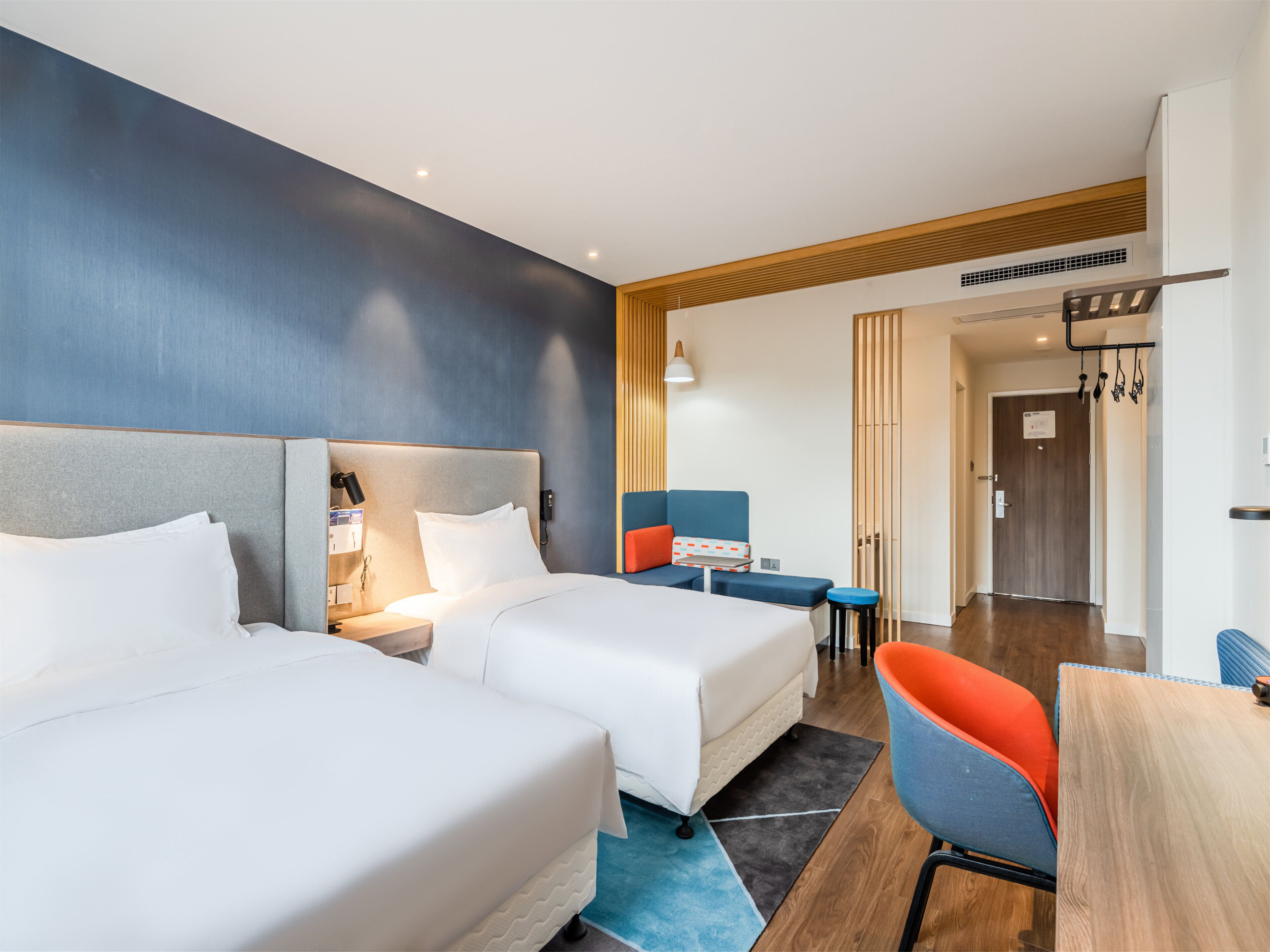 Une chambre d’hôtel avec deux lits, un bureau, une chaise et une porte de salle de bain.
