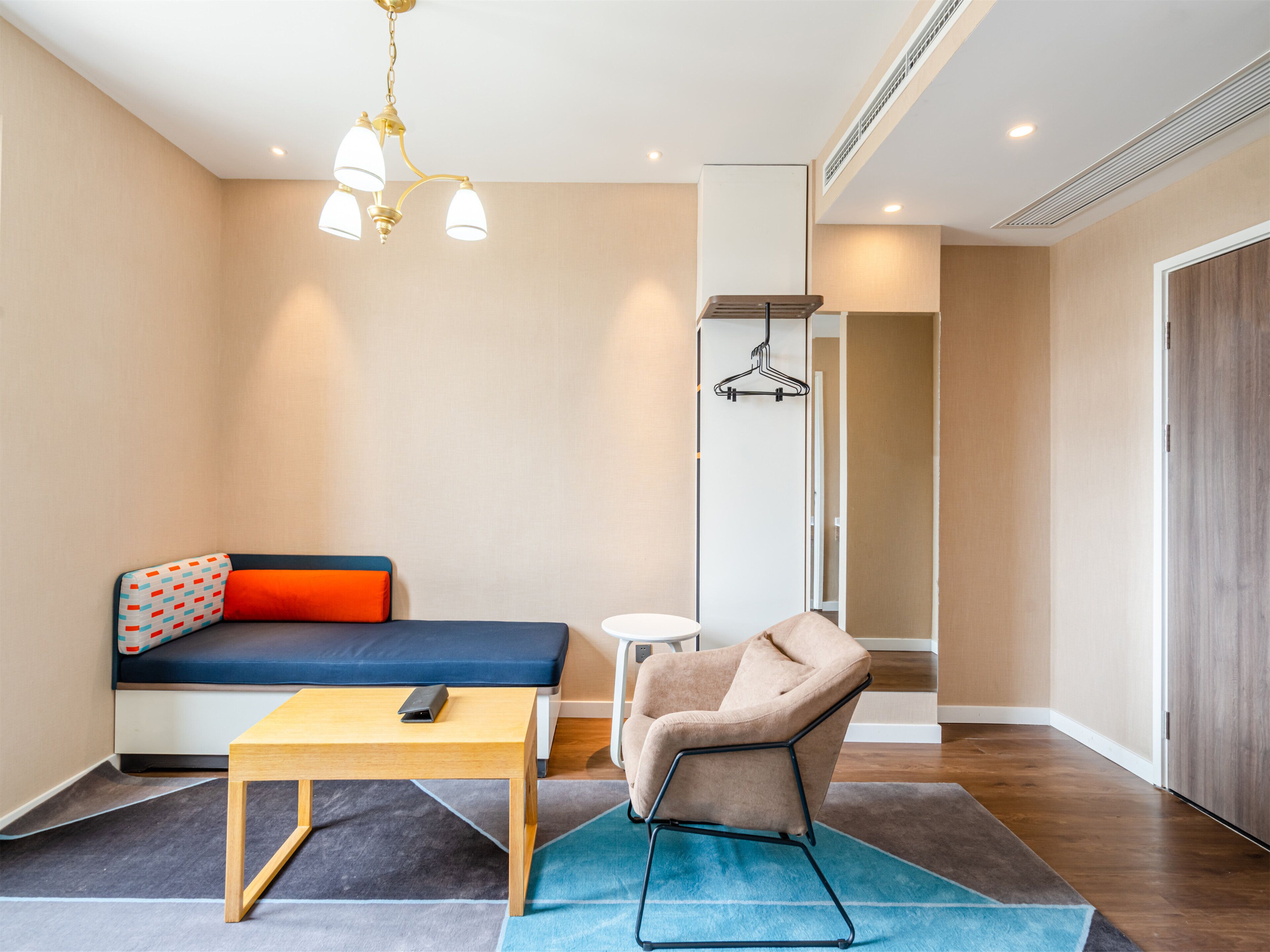 A modern room with a sofa, a chair, a small table, and a hanging light fixture.