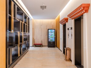 A hallway with a vending machine, a wooden floor, and an elevator. - Holiday Inn Express Litang by IHG (Garze)