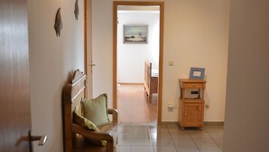 A hallway with a wooden bench, a small cabinet, and a door leading to another room. - Apartment at the port (Xanten)