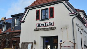 A white building with a red roof and the sign "Antik" on the front. - Apartment at the port (Xanten)