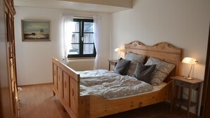 A wooden bed with a headboard, two bedside tables, and a window with curtains. - Apartment at the port (Xanten)