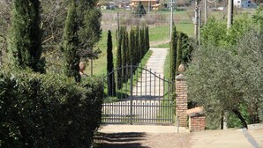 A gated entrance with a pathway leading to a building, surrounded by neatly trimmed hedges and trees. - Casa Legnaia, Tuscan Retreat in Castiglion Fiorentino (Castiglion Fiorentino)