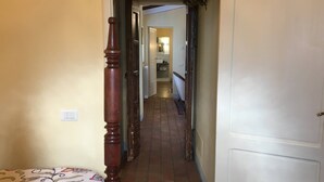A narrow hallway with a bed on the left, a door on the right, and a staircase leading to an upper floor. - Casa Legnaia, Tuscan Retreat in Castiglion Fiorentino (Castiglion Fiorentino)