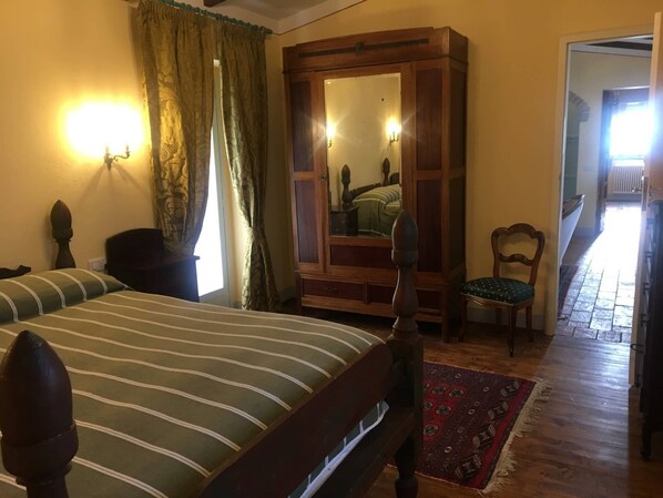 A bedroom with a bed, a wooden wardrobe, a chair, and a mirror. - Casa Legnaia, Tuscan Retreat in Castiglion Fiorentino (Castiglion Fiorentino)