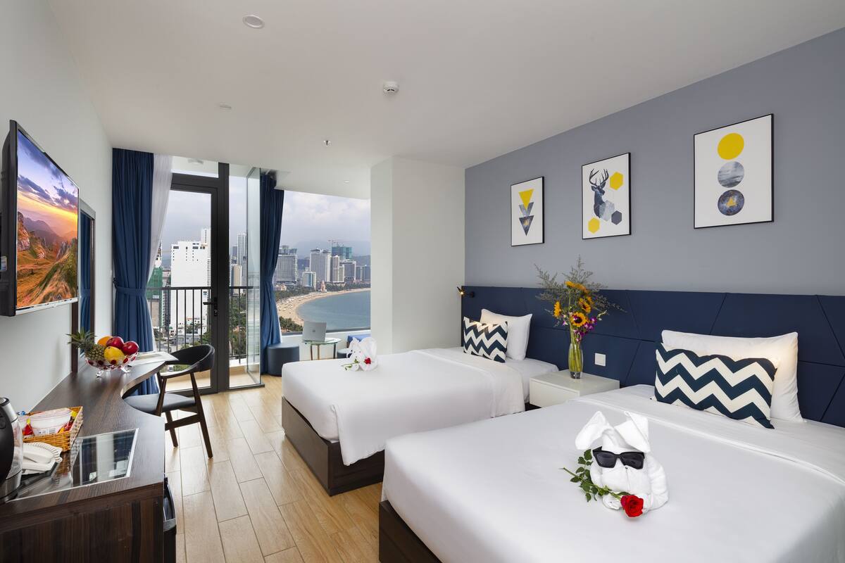 Une chambre d’hôtel moderne avec deux lits, un bureau et une vue sur la ville.