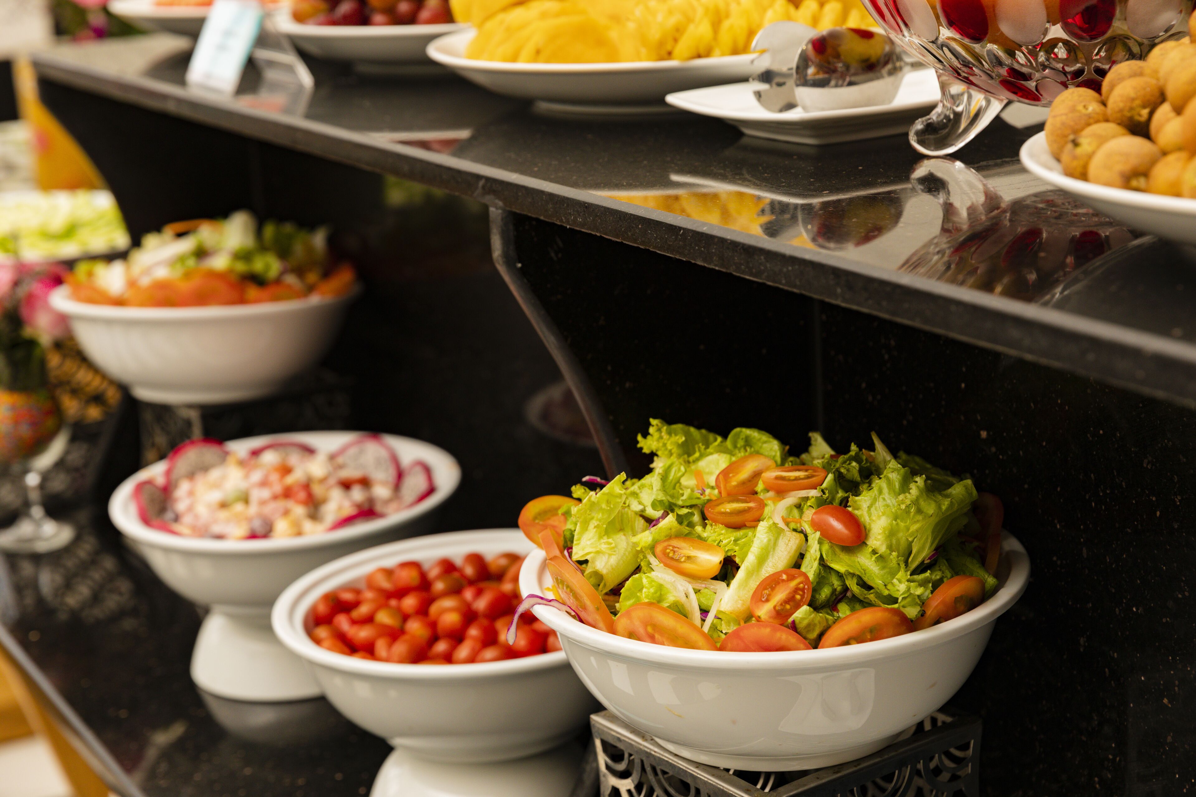 A buffet with various dishes including salads, fruits, and other food items.