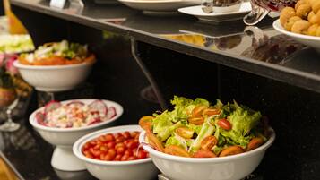 A buffet with various dishes including salads, fruits, and other food items.