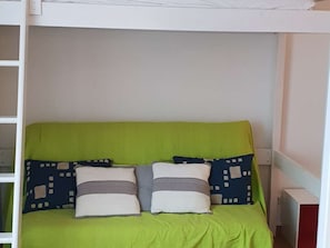 Un lit superposé avec un matelas vert et deux oreillers à motifs géométriques.