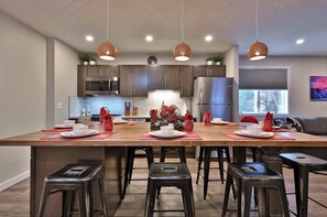 A modern kitchen with a large island, stainless steel appliances, and pendant lighting.