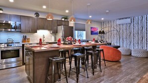 Una cocina moderna con electrodomésticos de acero inoxidable, armarios de madera y una isla central con taburetes.