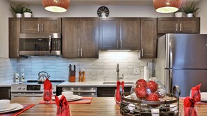 Una cocina moderna con armarios de madera oscura, electrodomésticos de acero inoxidable y una isla central adornada con servilletas rojas y objetos decorativos.