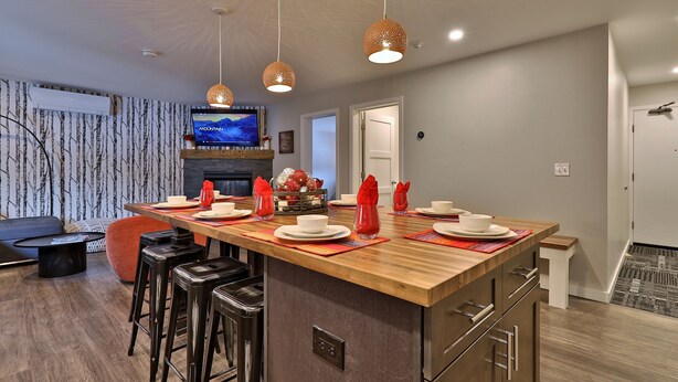 Una cocina moderna con una isla de madera, taburetes de bar e iluminación colgante.