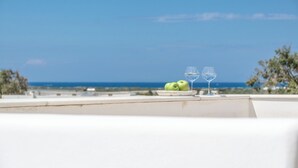 A terrace with a view of the sea, two green apples, and two empty wine glasses on a white table. - Rocks Naxian Villa, private Pool, by NaxosVibe (AGIA ANNA, NAXOS)