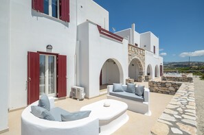 A white building with red shutters, stone arches, and a stone wall.