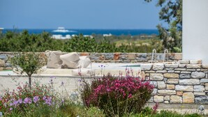 A stone wall, outdoor seating, and a view of the sea. - Rocks Naxian Villa, private Pool, by NaxosVibe (AGIA ANNA, NAXOS)