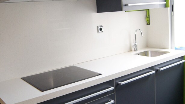Una cucina moderna con cappa in acciaio inossidabile, lavello integrato e una combinazione di colori bianco e nero.