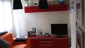 Un soggiorno moderno con un'unità di intrattenimento rossa, una televisione a schermo piatto e un'ampia finestra.