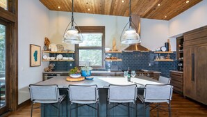 A modern kitchen with a large island, bar stools, pendant lights, and a wooden ceiling. - Lake View Home with Private Hot Tub (Tahoma)