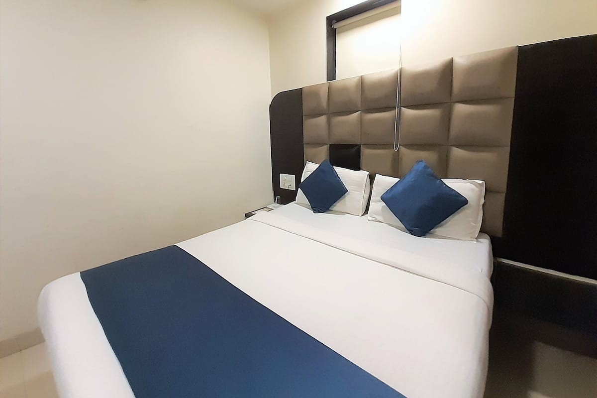 A hotel room with a bed, a headboard, and a wall-mounted clock.